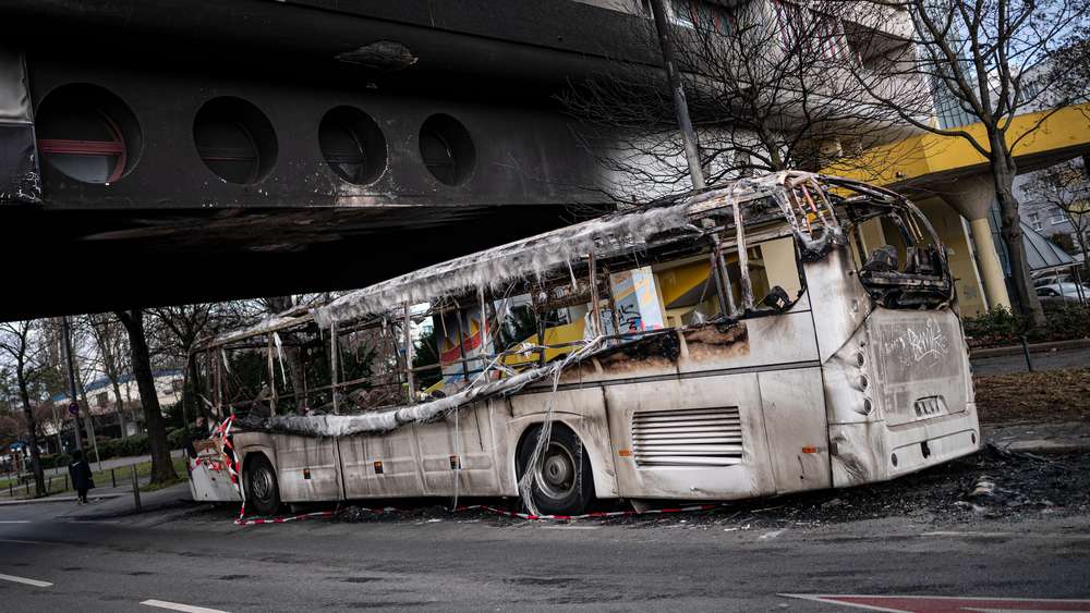 Po silvestrovských nepokojích stojí před poškozenou obytnou budovou v berlínské čtvrti Neukölln vyhořelý autobus